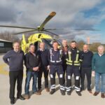 A group of people standing in front of a yellow helicopter